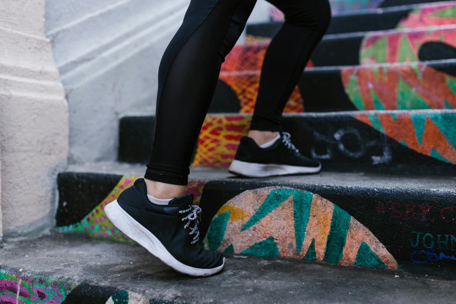Close-up of a person walking up colorful graffiti stairs wearing sneakers. on Think Lean Live Strong