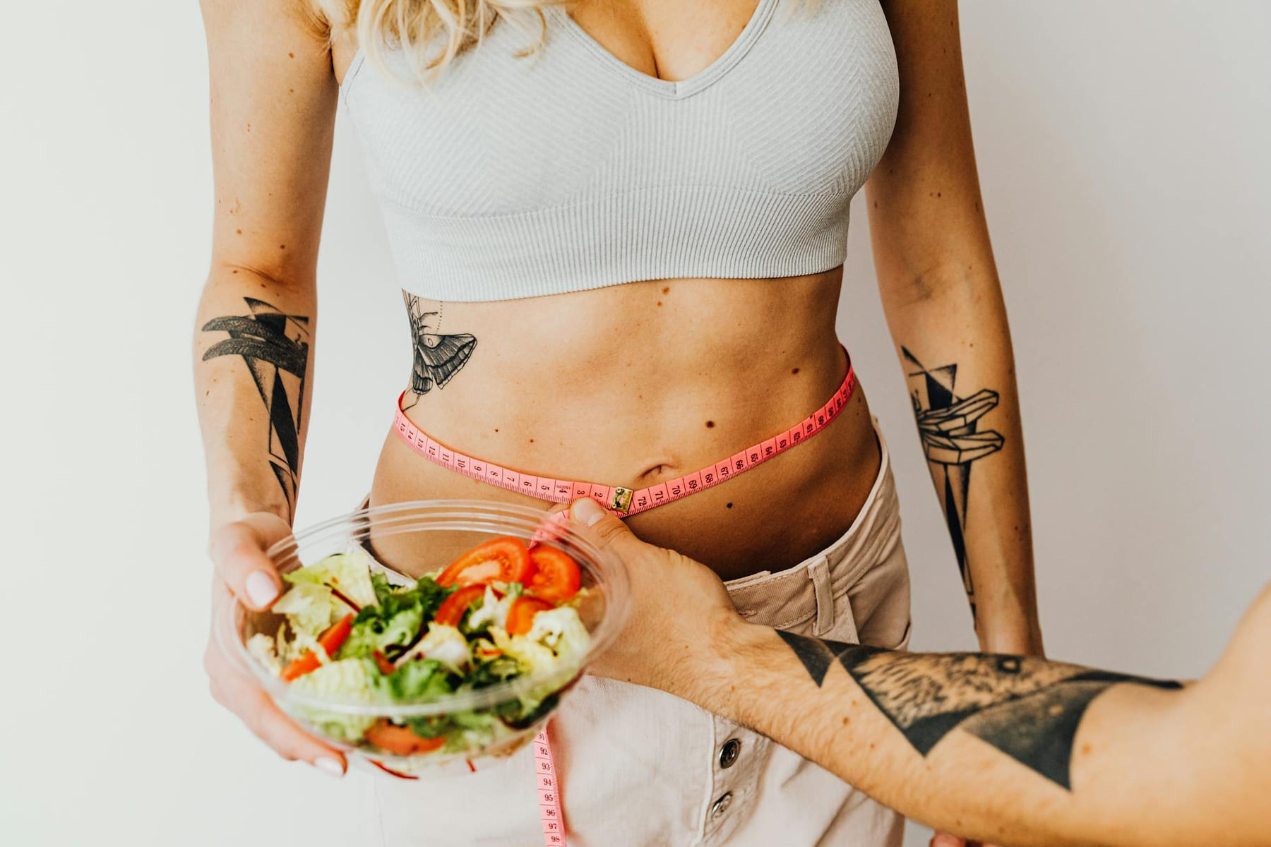 Fit woman measuring waist while holding a healthy salad bowl on Think Lean Live Strong