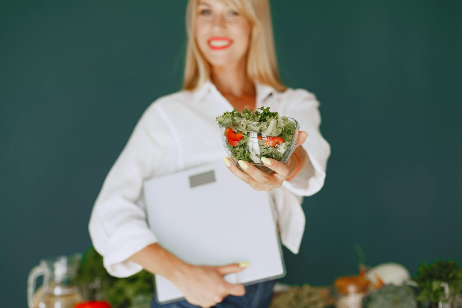 A woman with a vibrant smile offering a fresh salad bowl, promoting healthy eating. on Think Lean Live Strong