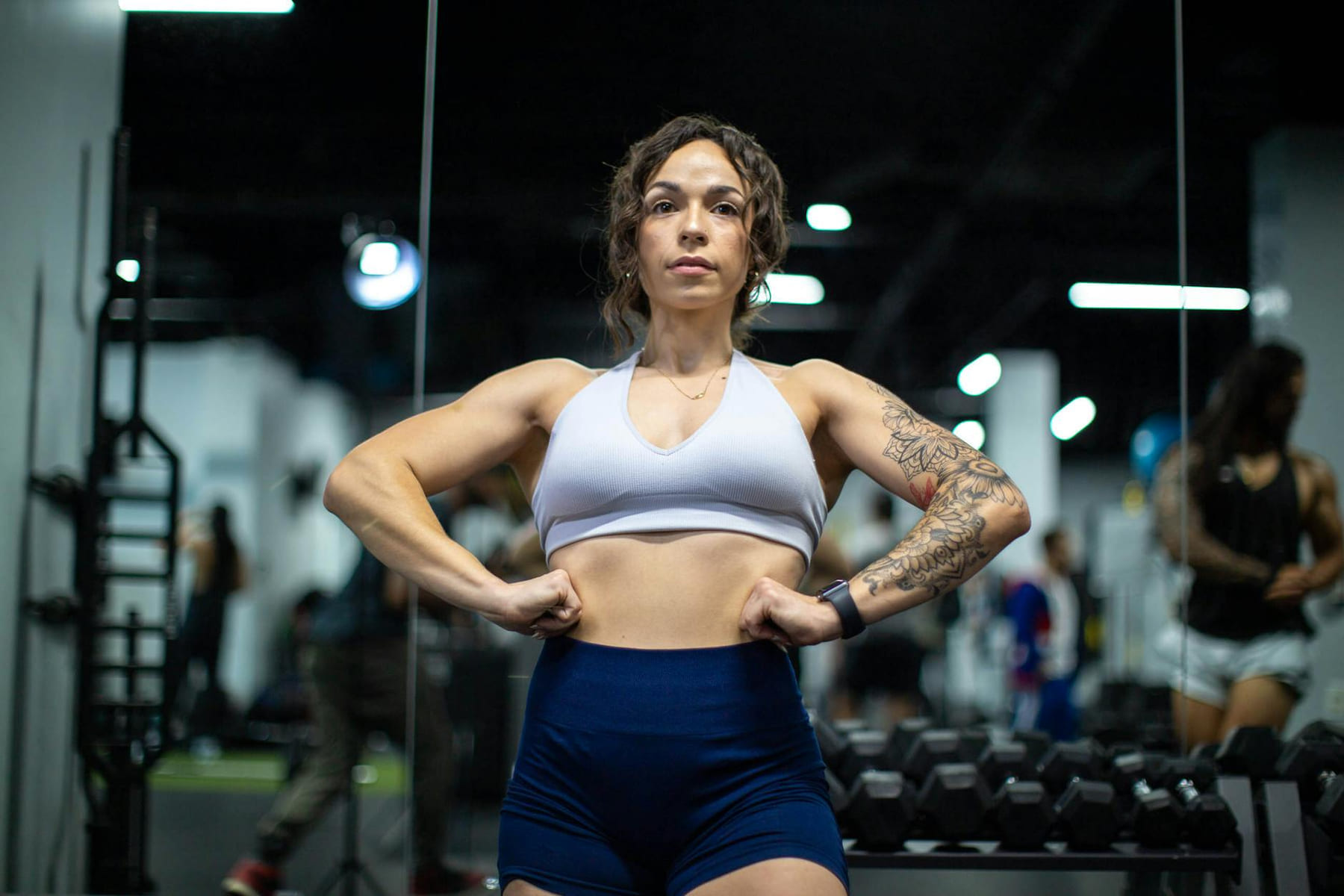 Strong woman in sports bra flexing her muscles in a gym for fitness motivation. on Think Lean Live Strong