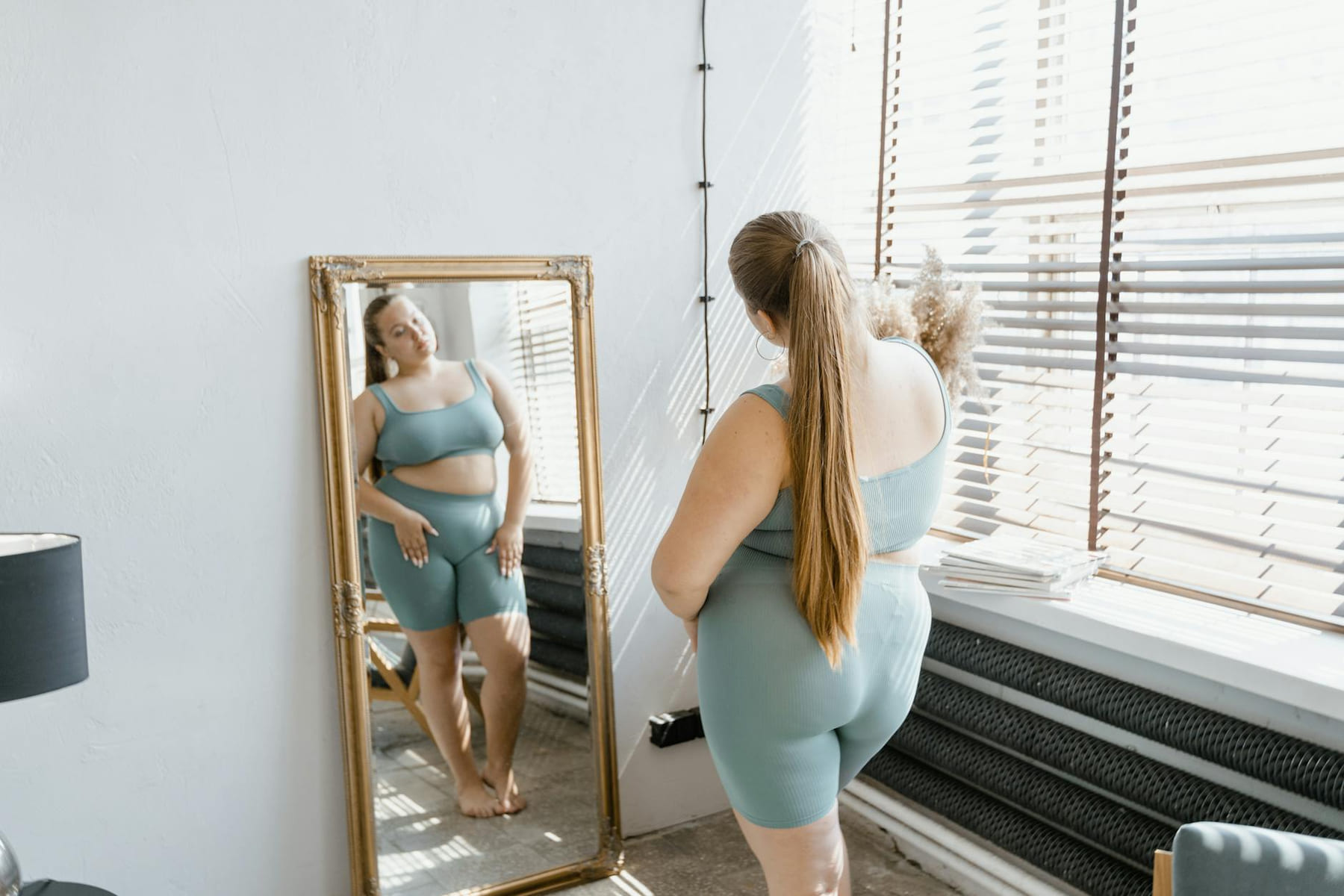 A woman in activewear reflects on her image in a stylish mirror indoors. on Think Lean Live Strong