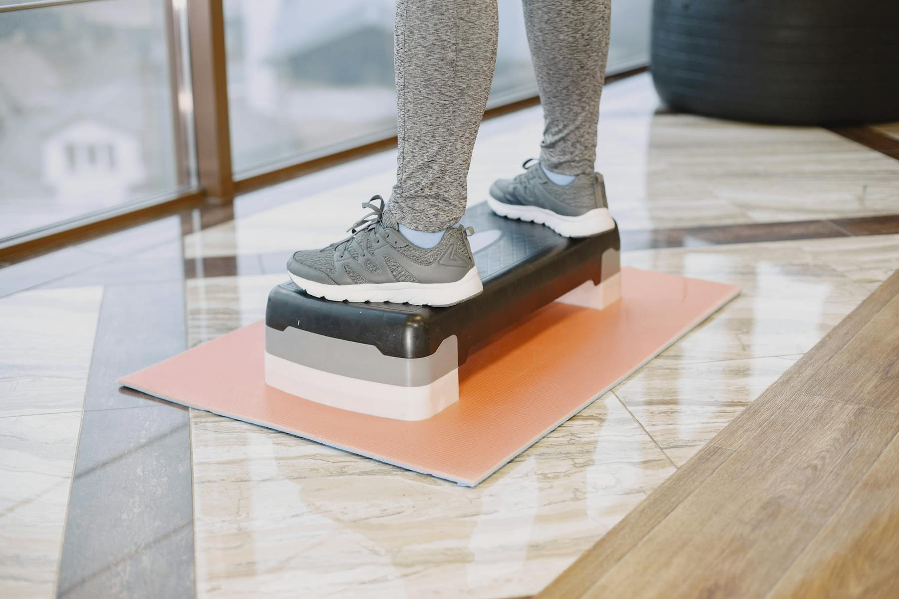 A person exercising indoors using a step platform for a workout routine. on Think Lean Live Strong
