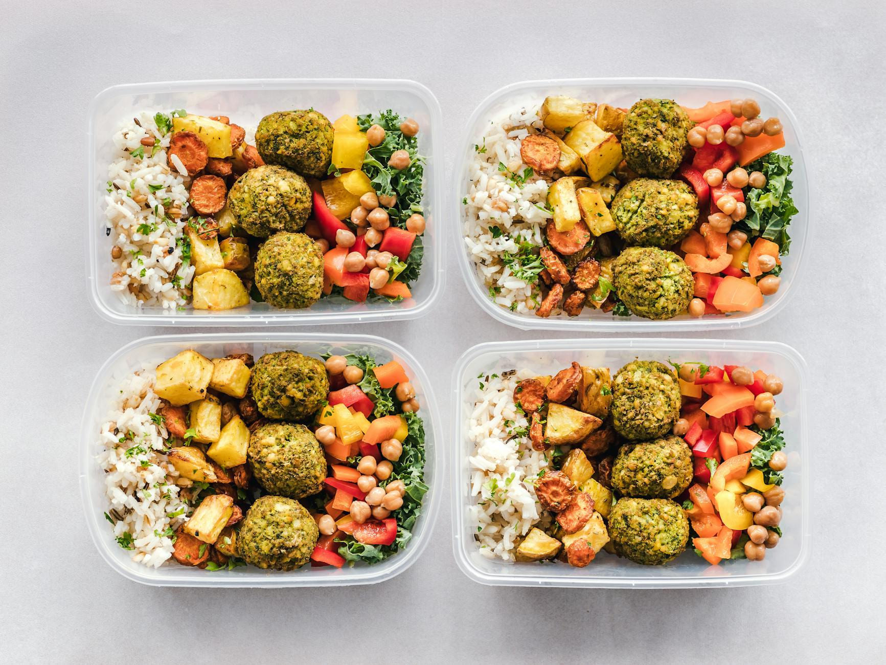 Colorful meal prep containers with falafel, chickpeas, rice, and vegetables for a healthy lifestyle. on Think Lean Live Strong