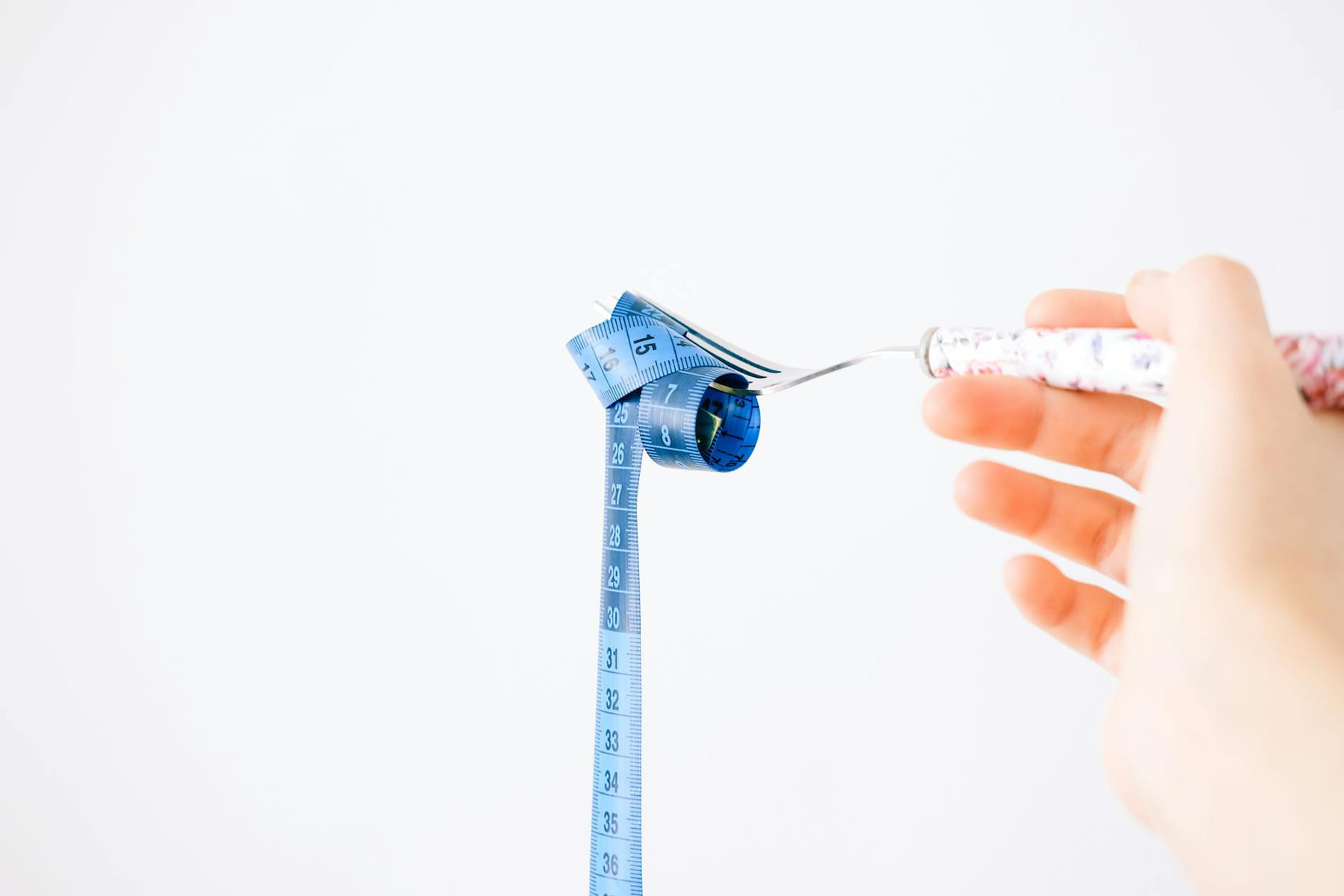 A blue measuring tape wrapped around a fork representing dieting or healthy eating concept. on Think Lean Live Strong
