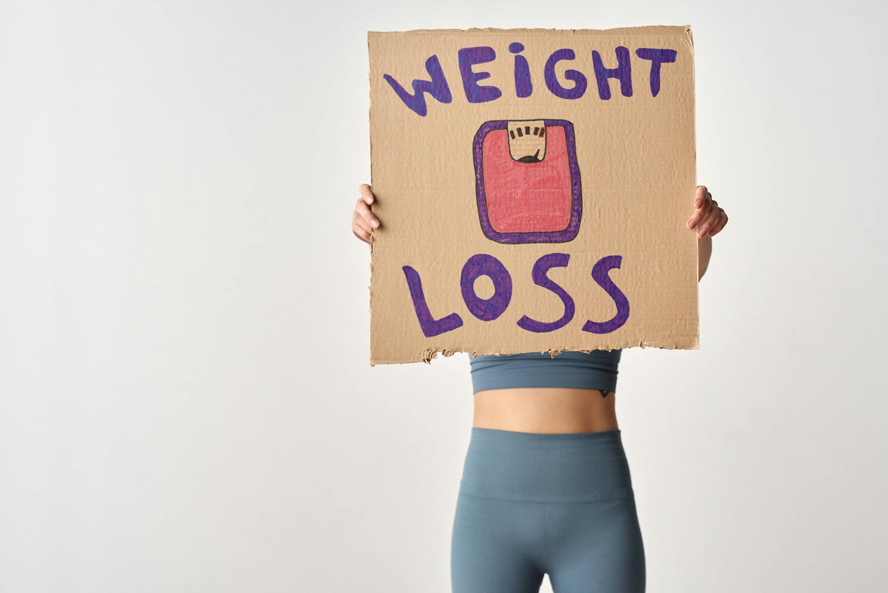 Person holding 'weight loss' sign for fitness motivation and health goals. on Think Lean Live Strong
