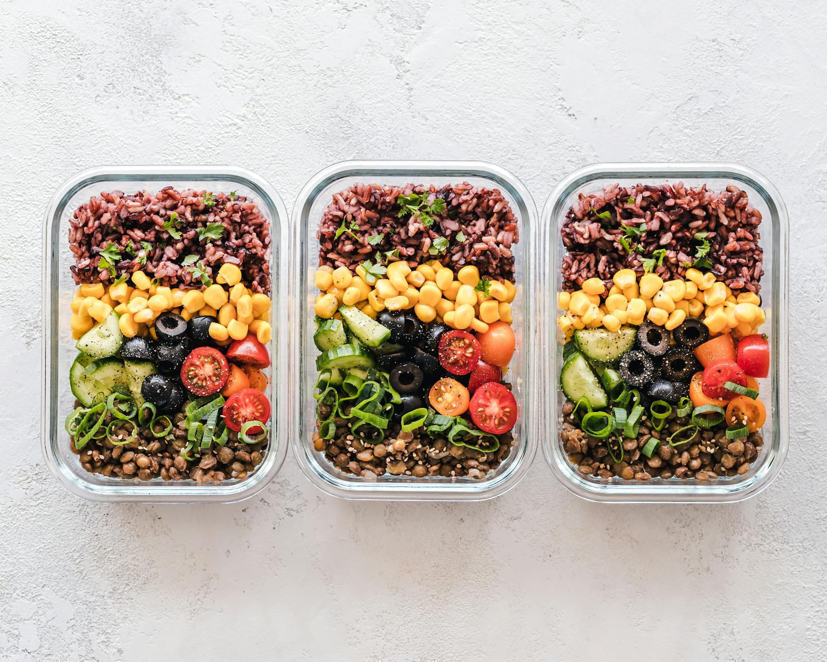 Colorful healthy meal prep with corn, olives, tomatoes, and lentils in glass containers. Perfect for mindful eating. on Think Lean Live Strong