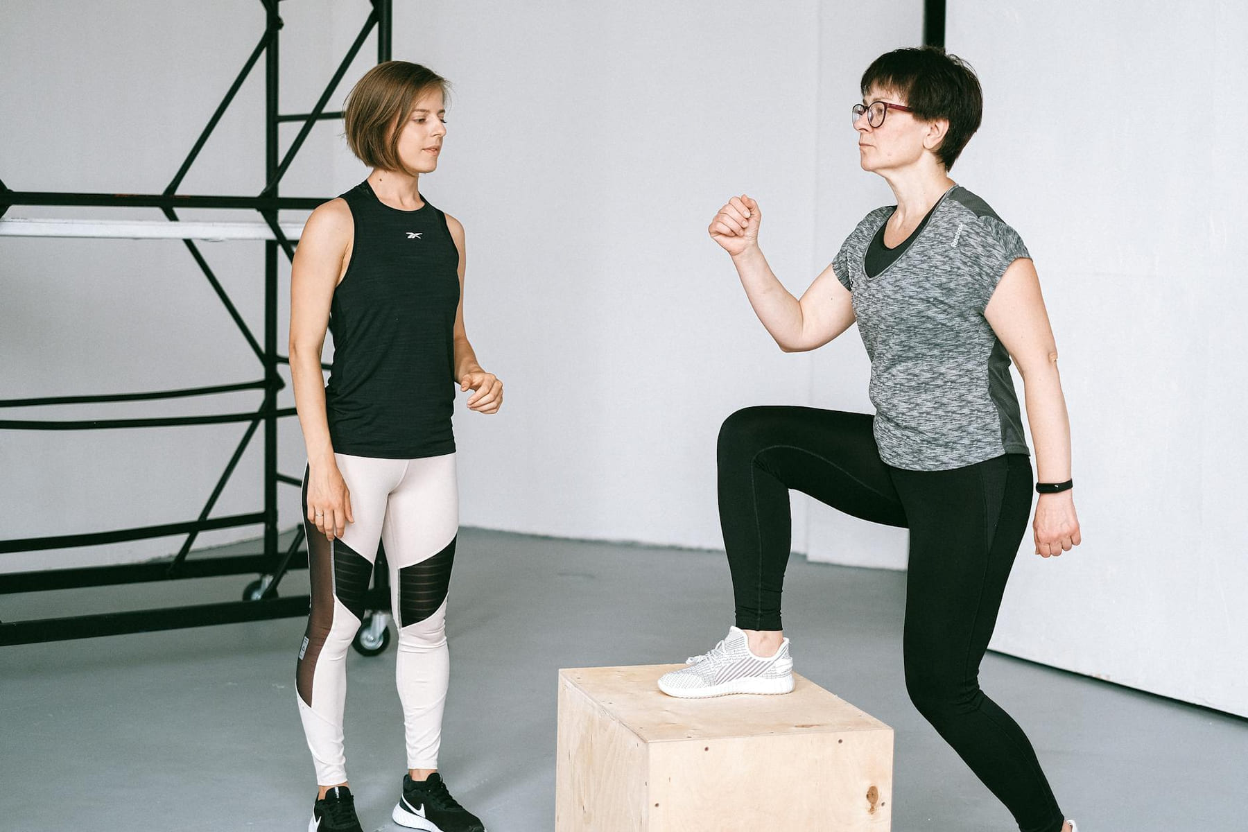 Fitness coach guides a woman in workout indoors. Focus on exercise and healthy lifestyle. on Think Lean Live Strong
