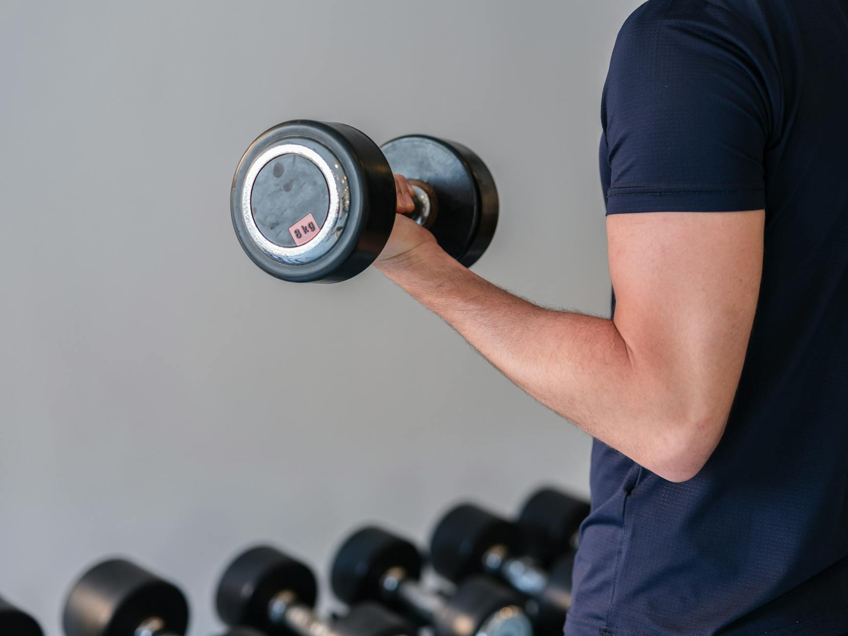 Close-up of a man lifting a dumbbell in a gym, emphasizing fitness and strength training. on Think Lean Live Strong