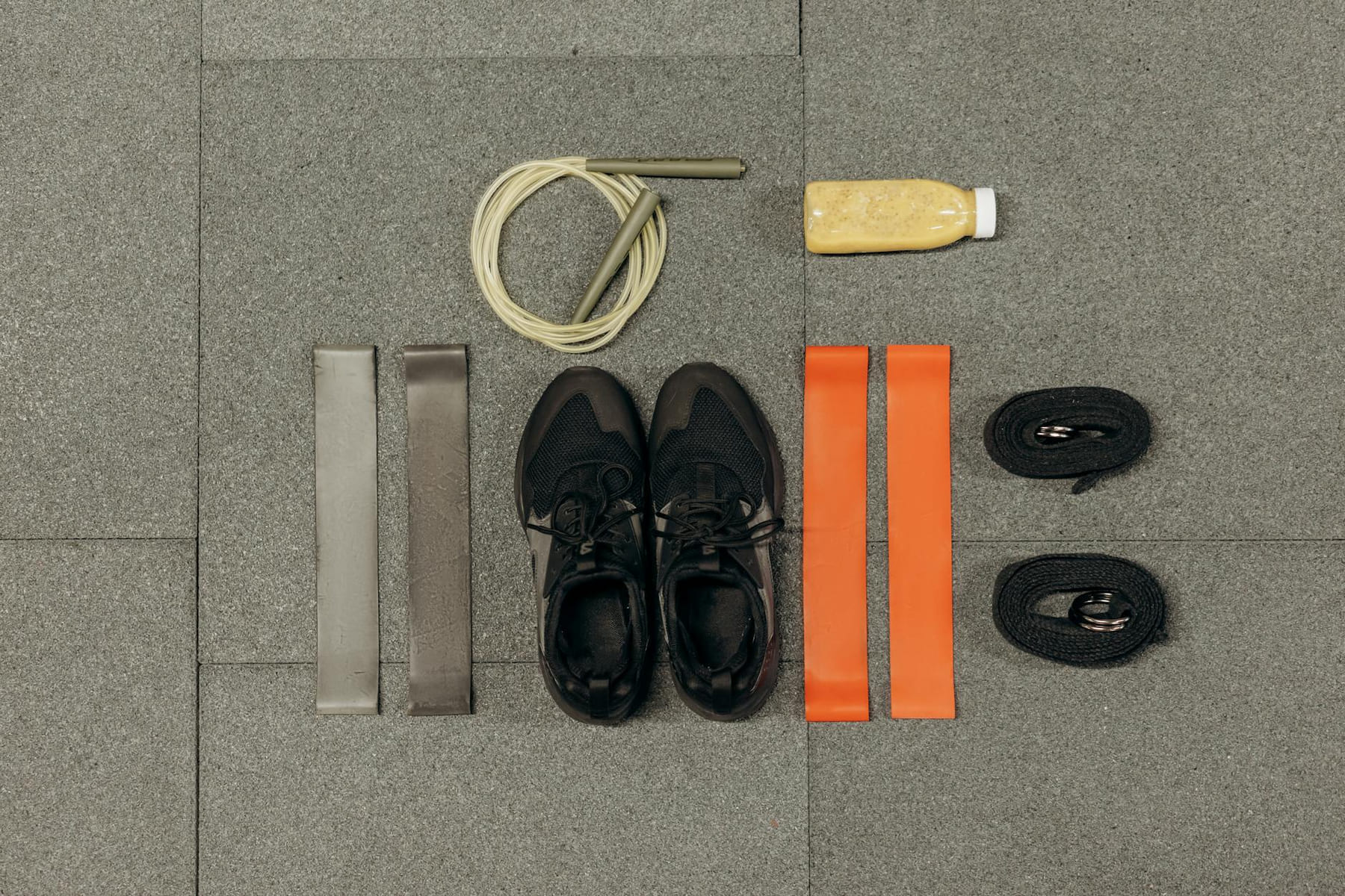 A neatly arranged flatlay featuring fitness equipment and a healthy drink on a gray surface. on Think Lean Live Strong